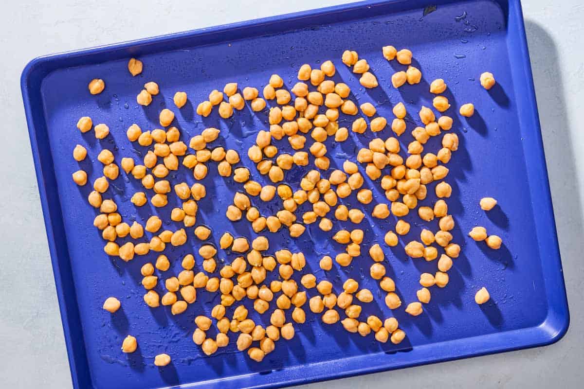 An overhead photo of canned chickpeas spread out on a sheet pan.