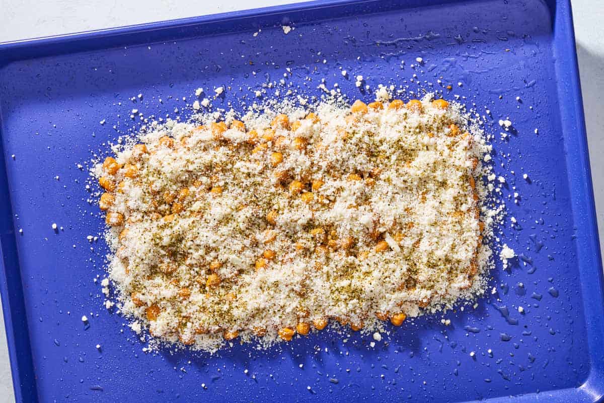 An overhead photo of cooked chickpeas topped with parmesan and oregano on a sheet pan.