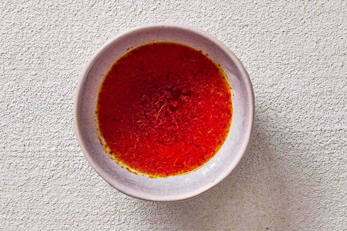 An overhead photo of saffron blooming in water in a small bowl.