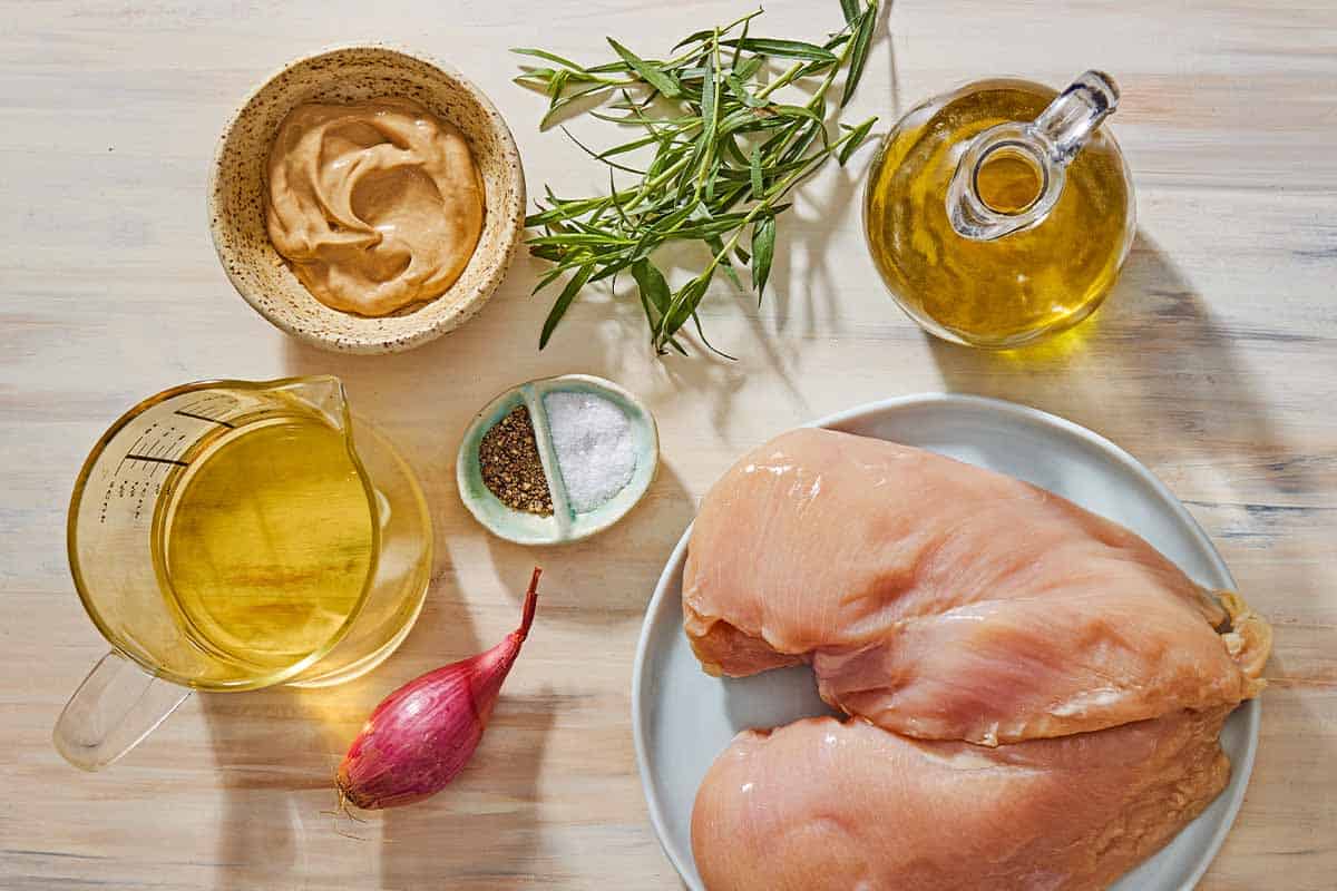 Ingredients for chicken with tarragon mustard sauce including chicken breasts, salt, black pepper, olive oil, a shallot, white wine, dijon mustard and fresh tarragon.