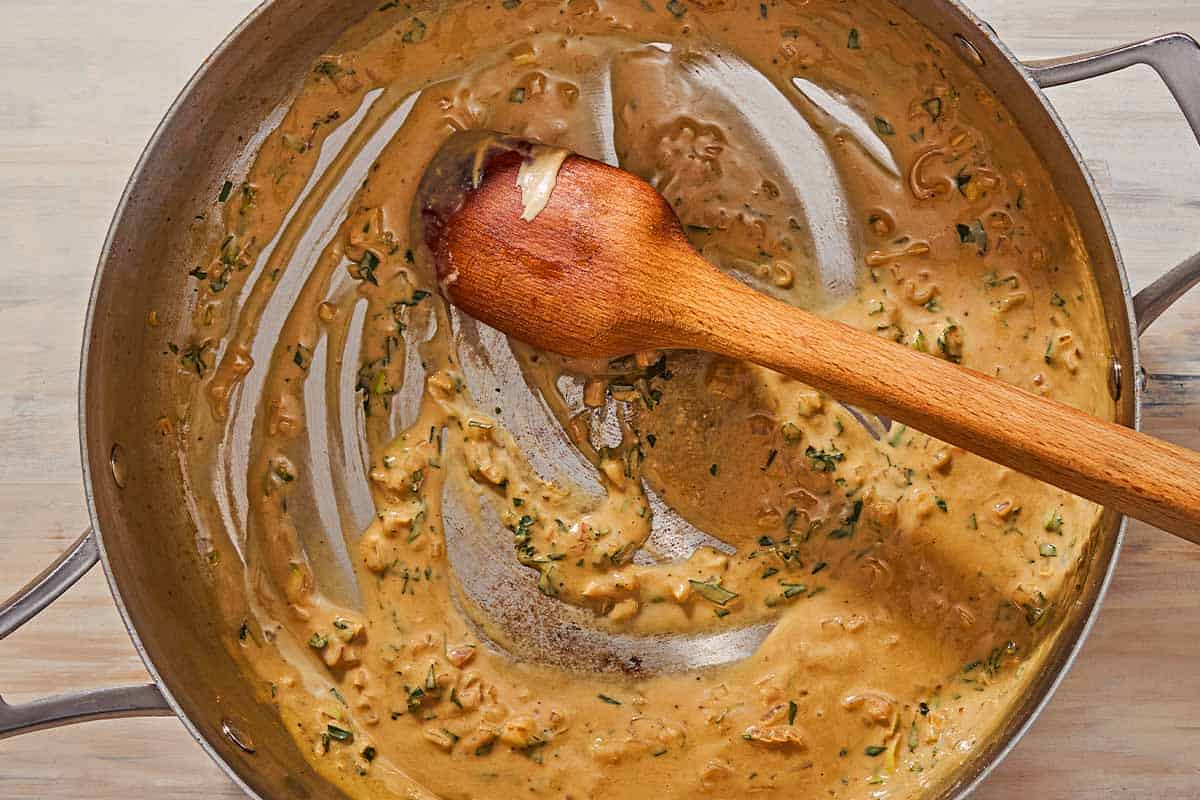 An overhead photo of the tarragon mustard sauce in a skillet with a wooden spoon.