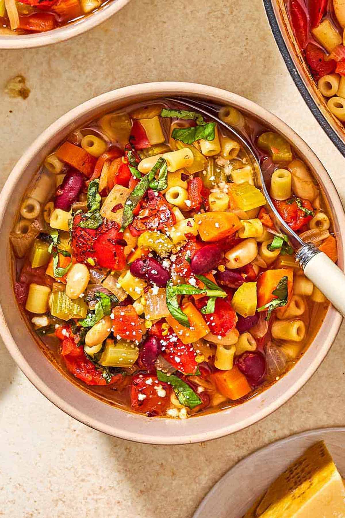 An overhead photo of a bowl of pasta fagioli with a spoon.