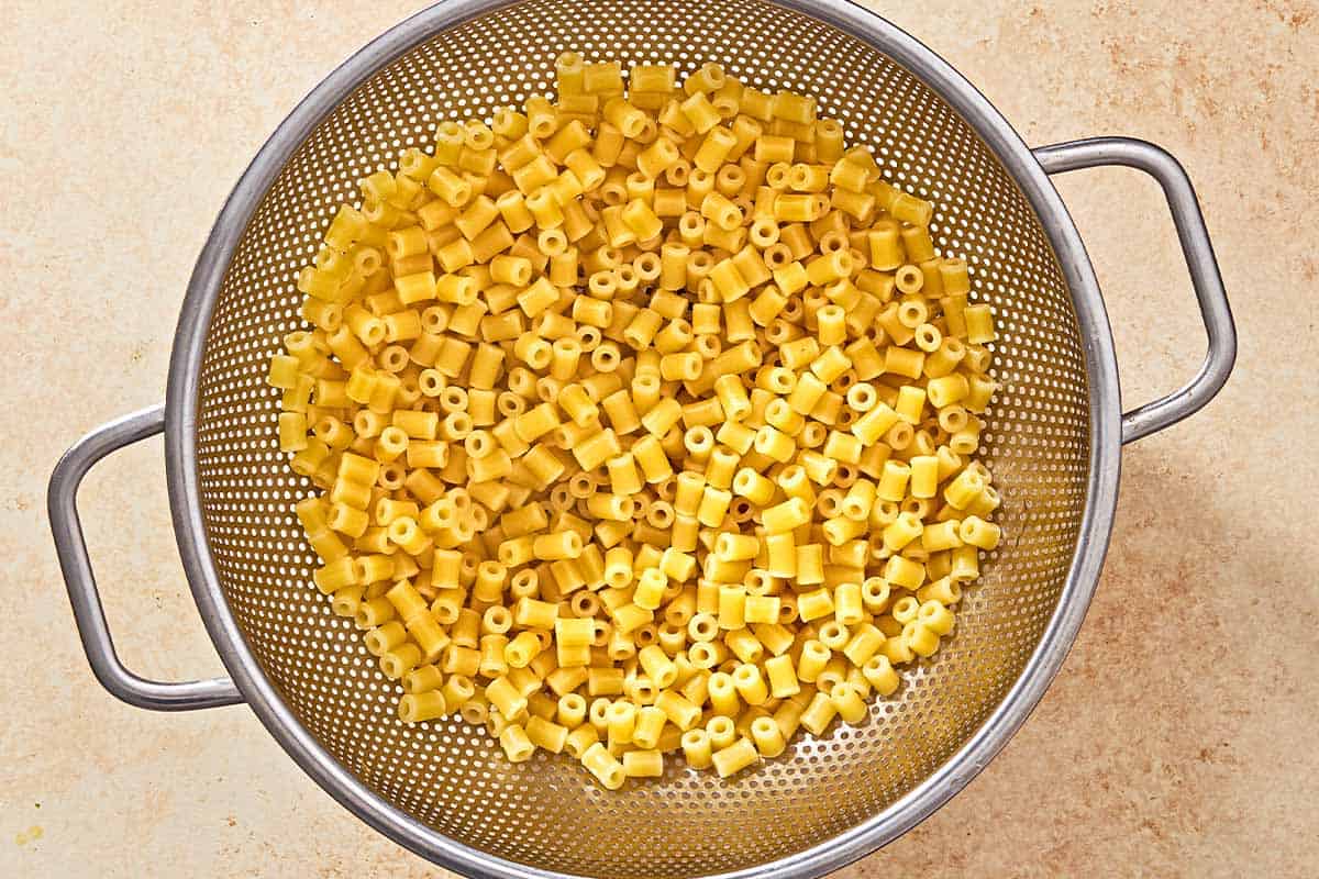 An overhead photo of cooked ditalini pasta in a strainer.