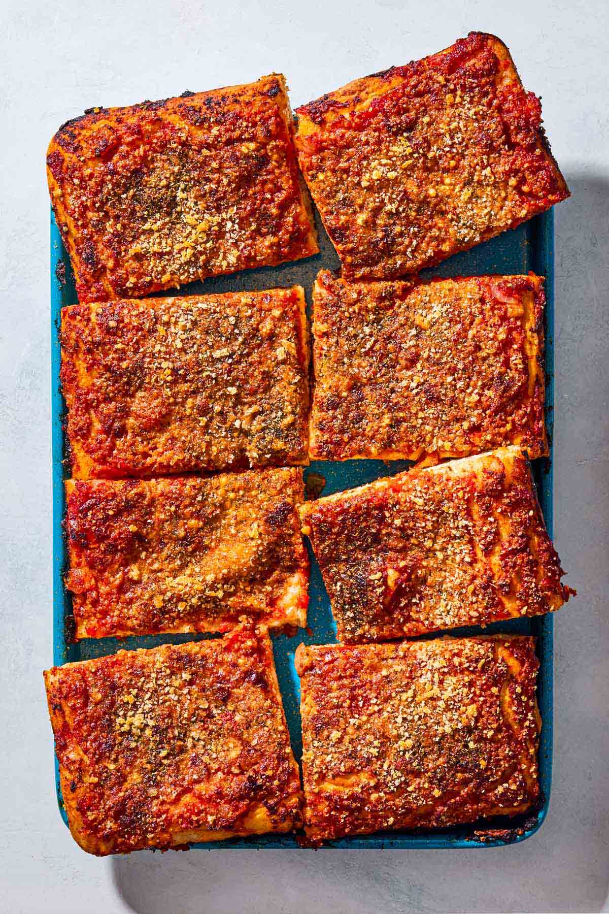 An overhead photo of several slices of sfincione sicilian pizza on a baking sheet.