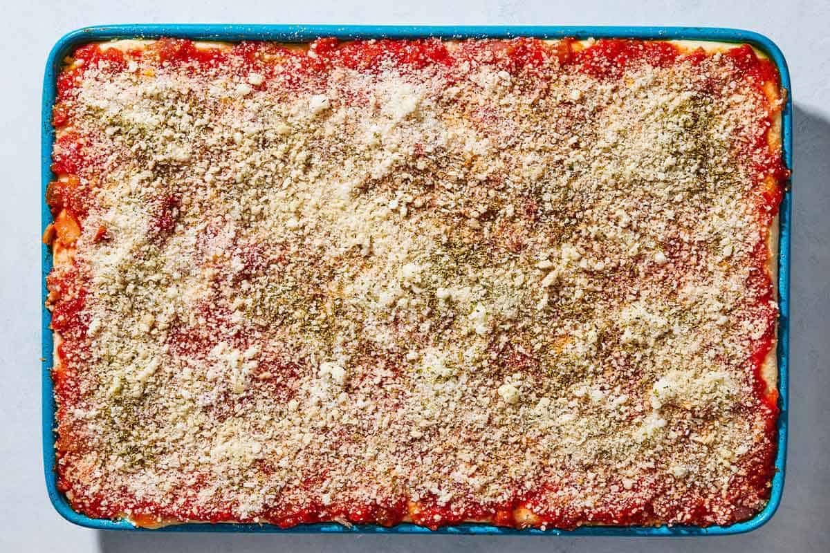 An overhead photo of unbaked sfincione sicilian pizza on a baking sheet.