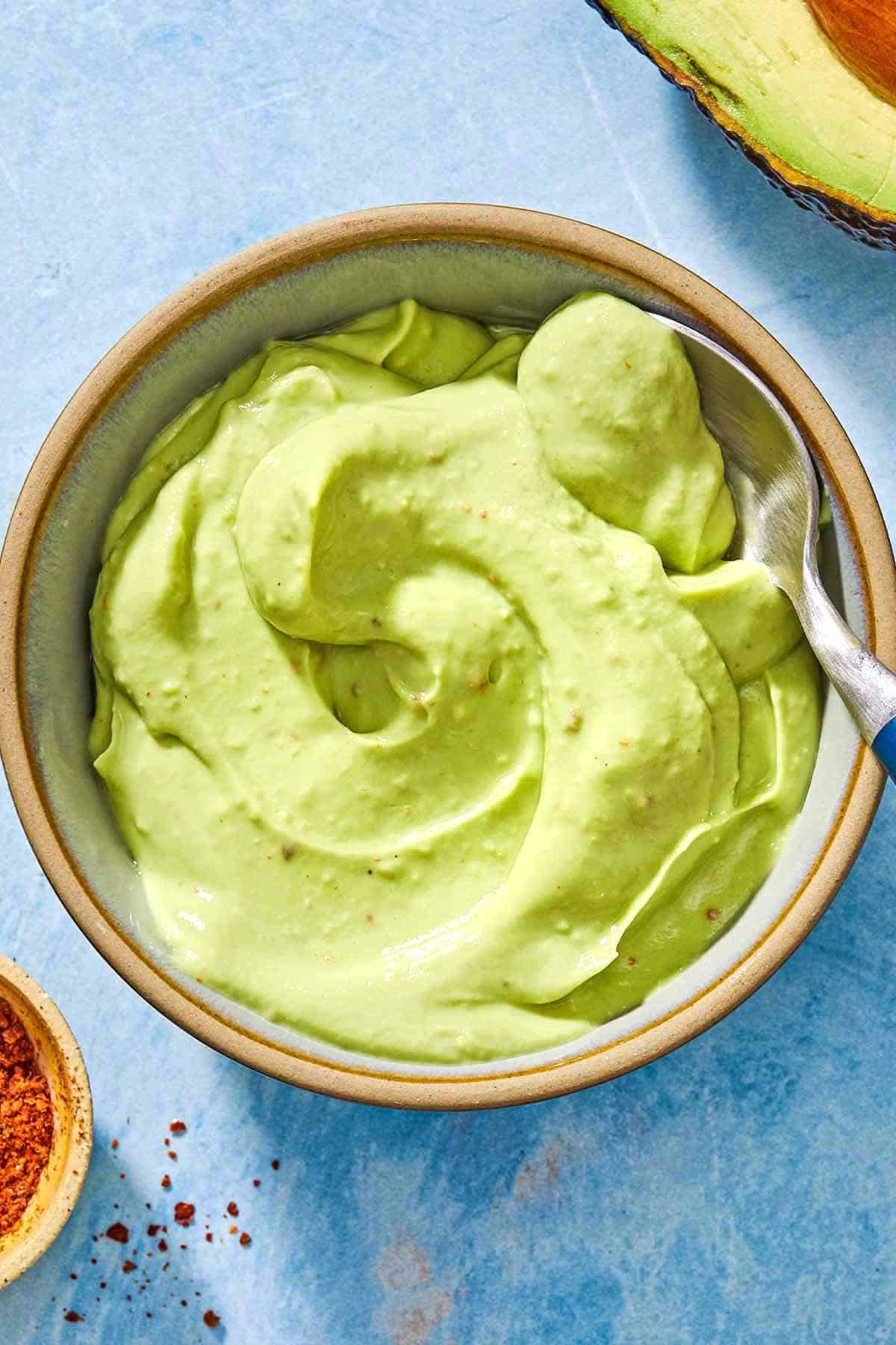 An overhead photo of avocado crema in a bowl with a spoon.