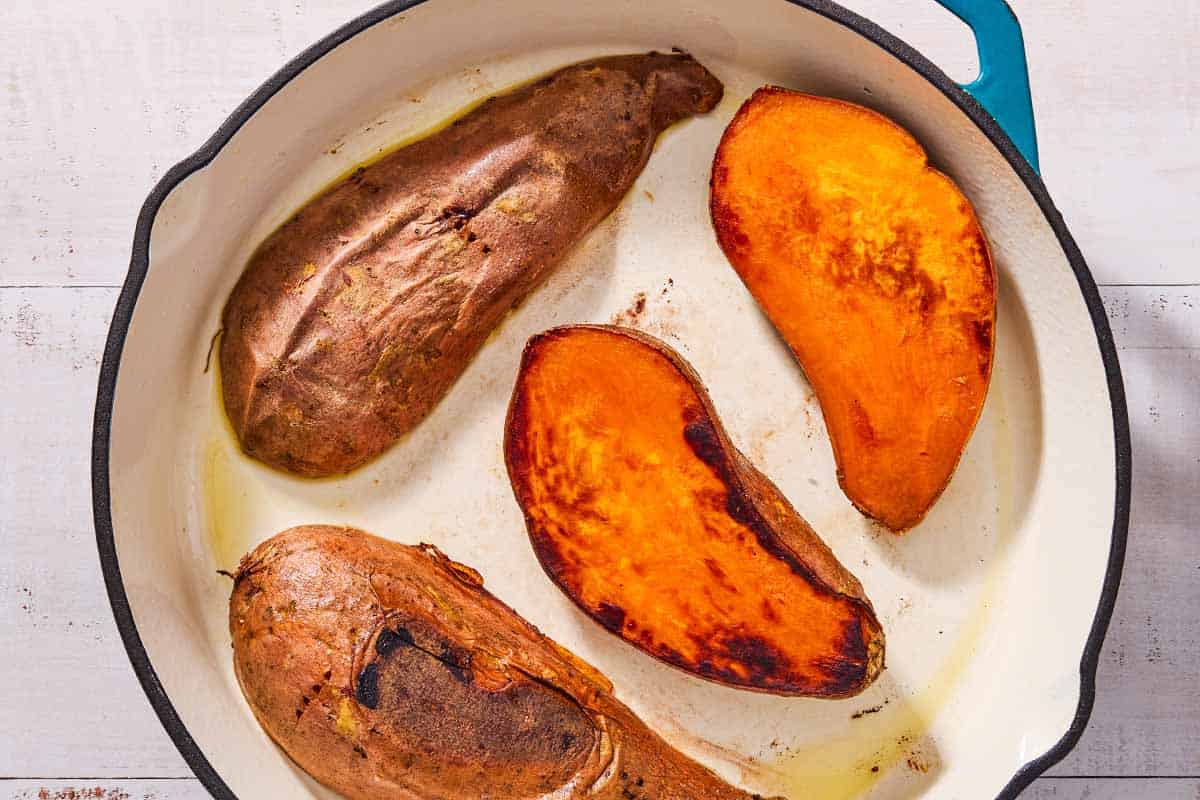 An overhead photo of 4 baked sweet potato halves in a skillet.