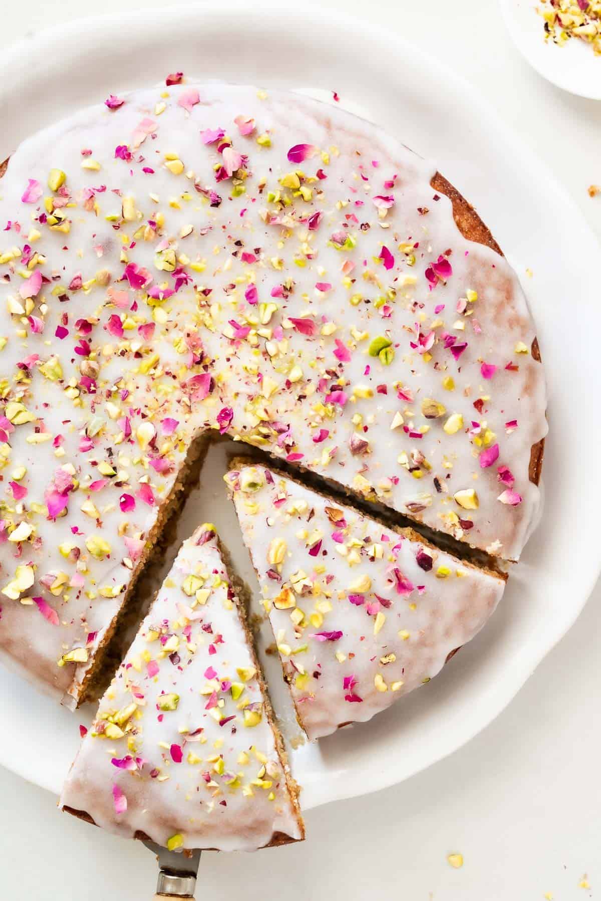 Overhead shot of Persian love cake on a platter with two slices cut out.