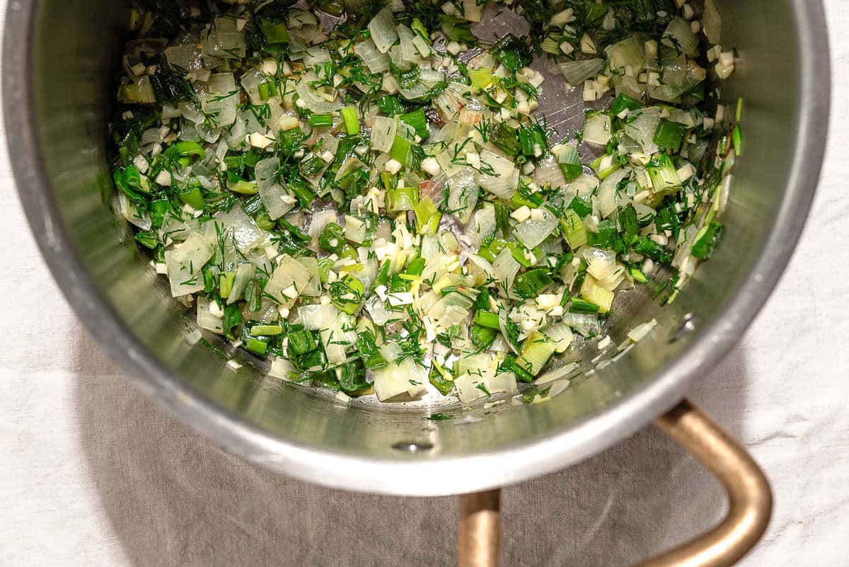 An overhead photo of the chopped vegetables for the spinach soup recipe in a large pot after being sauteed.