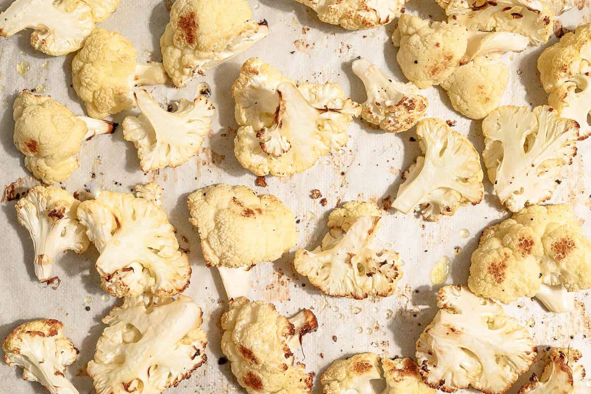 A close up of roasted cauliflower florets in a baking sheet.