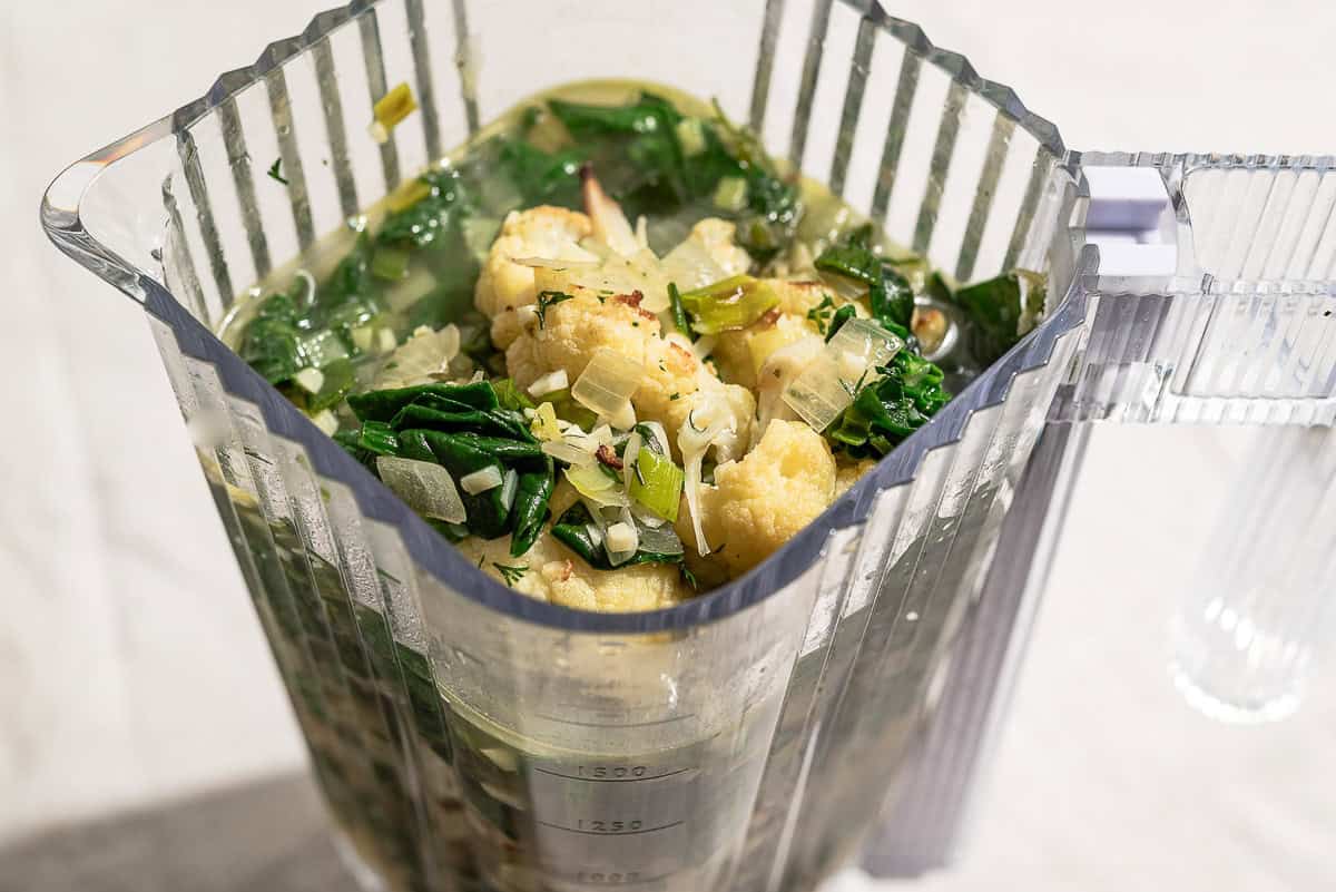 The cooked ingredients for the spinach soup recipe in a blender.