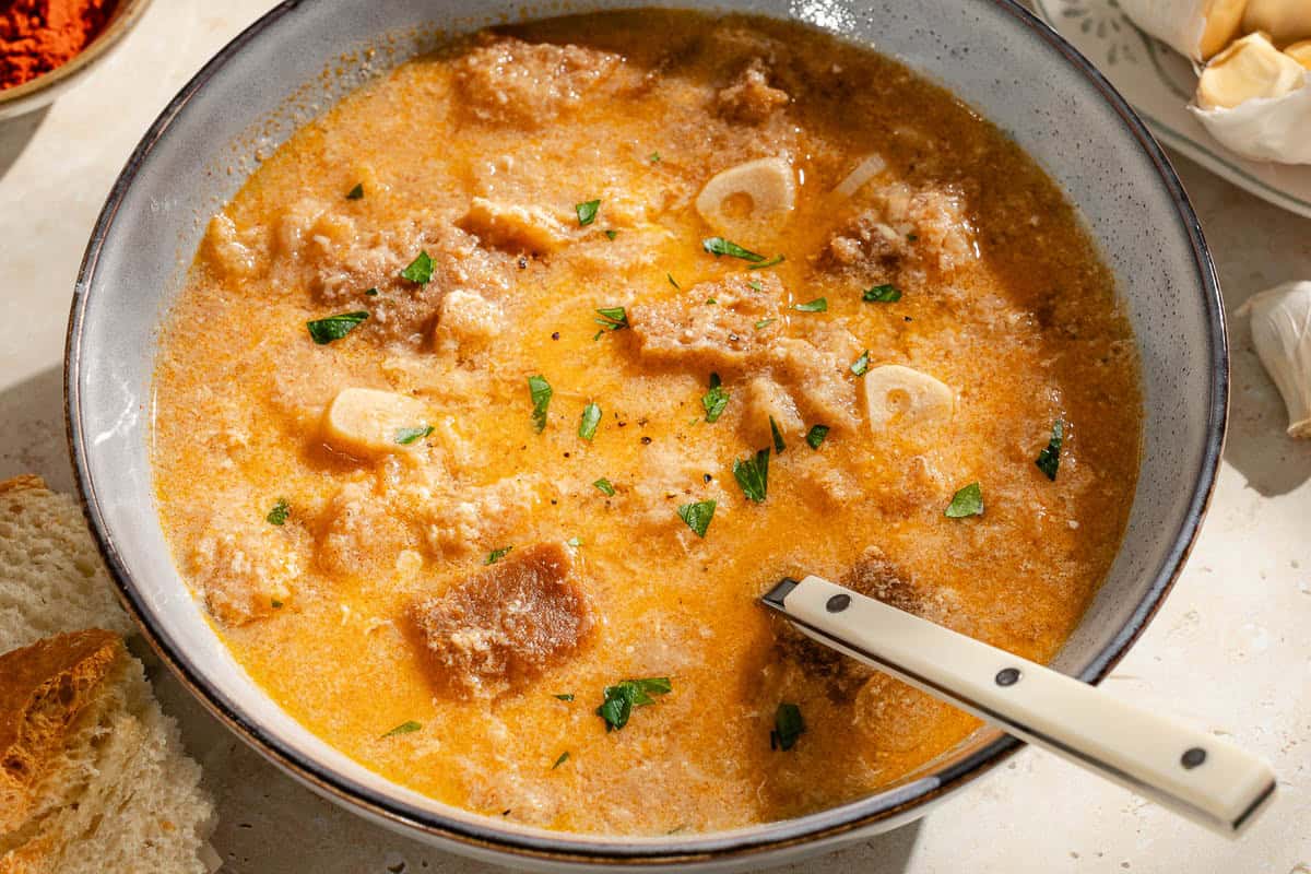 A close up of a bowl of sopa de ajo with a spoon.