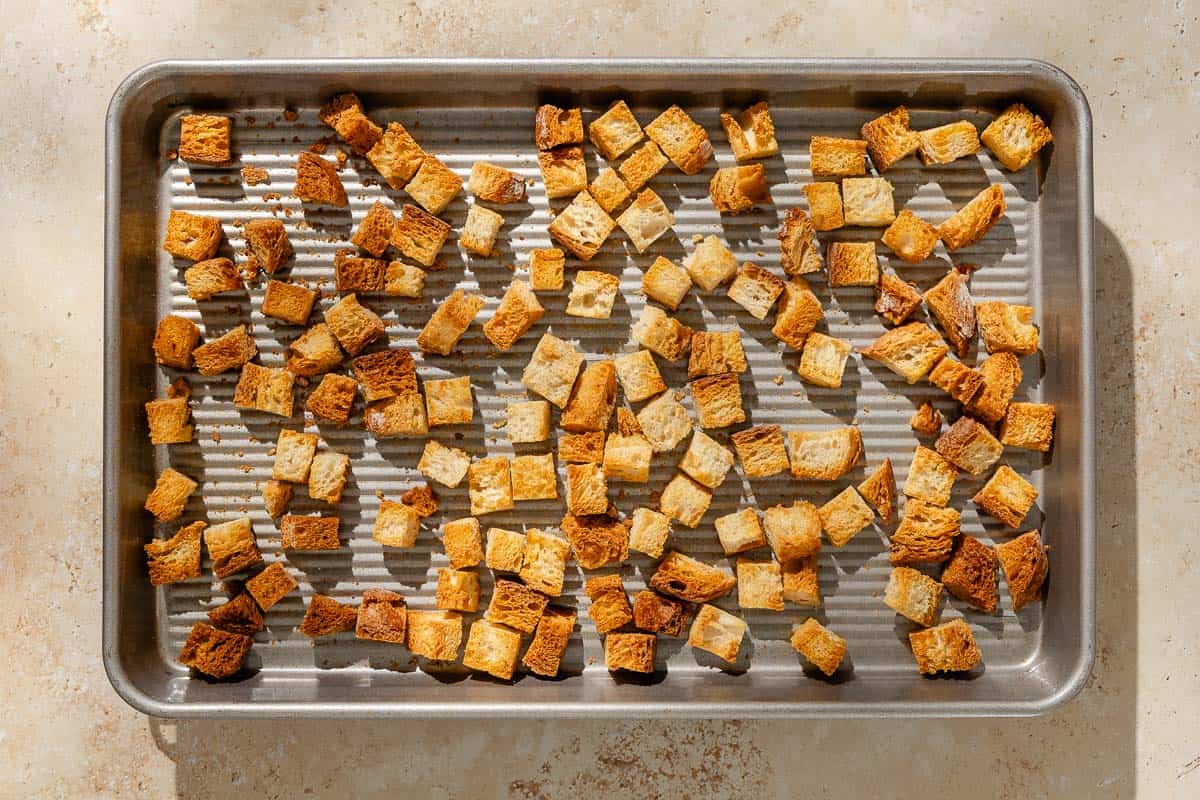 An overhead photo of toasted cubes of bread on a baking sheet.