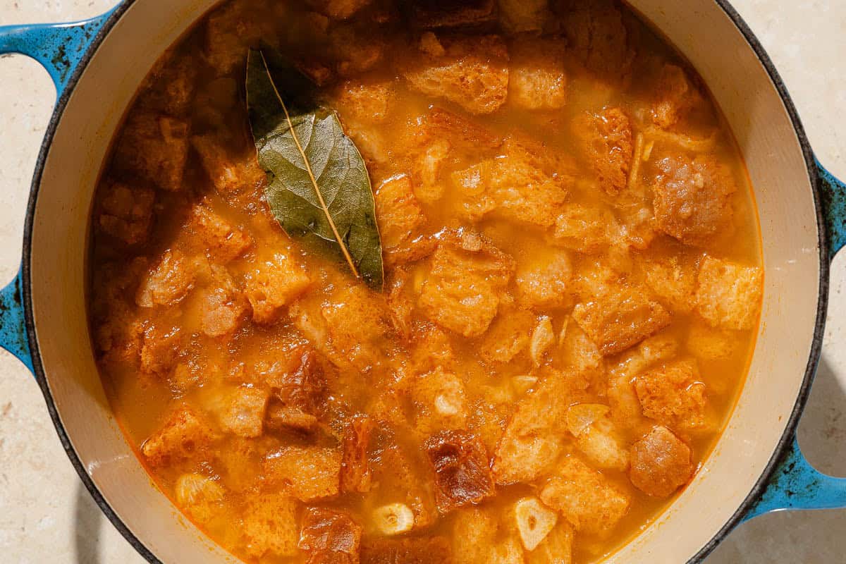 An overhead photo of sopa de ajo in a large pot with a bay leaf.