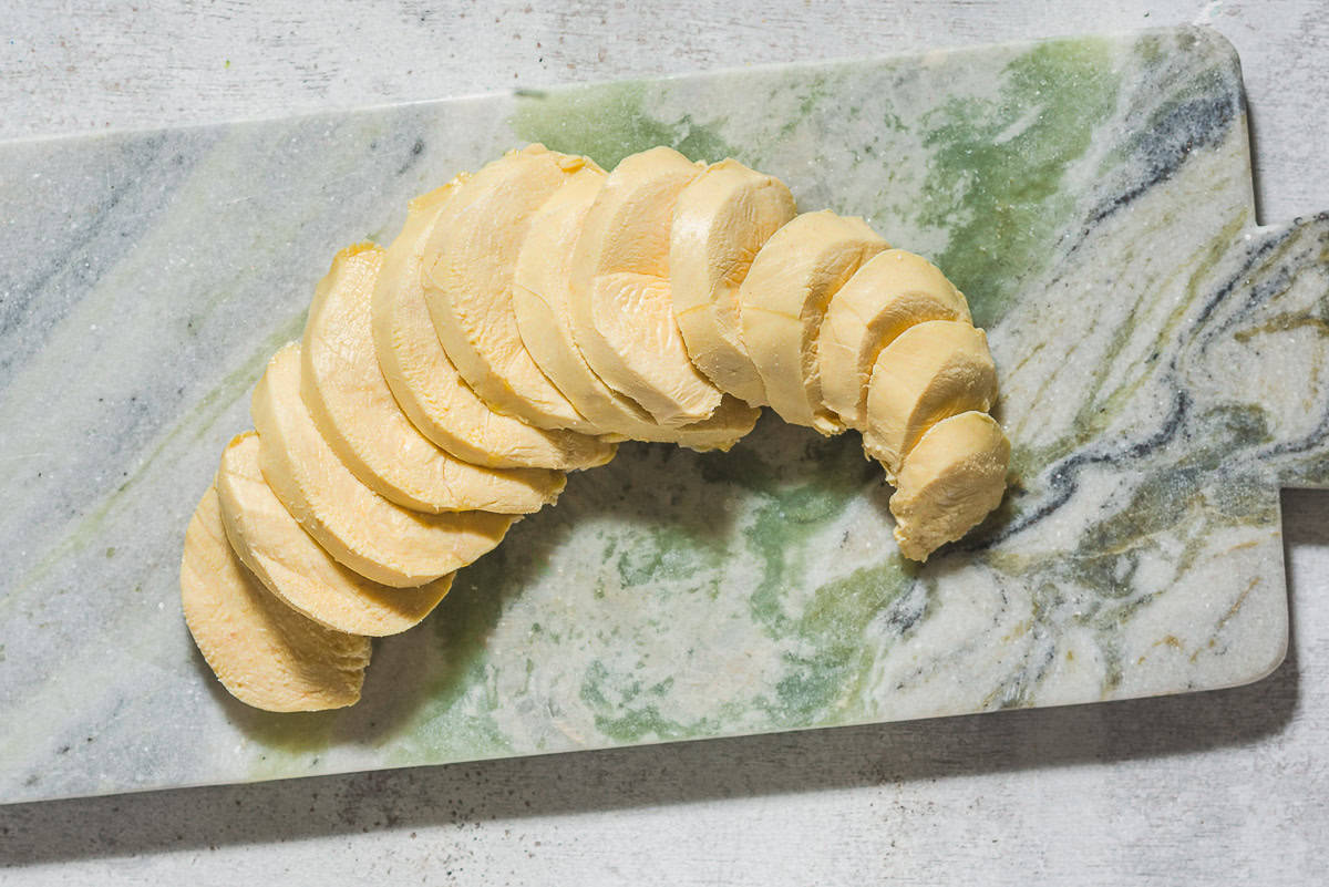 An overhead photo of a sliced poached chicken breast on a cutting board.