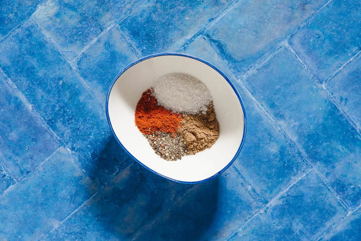 An overhead photo of the seasonings for the roasted salmon and vegetables in a bowl just before being mixed together.