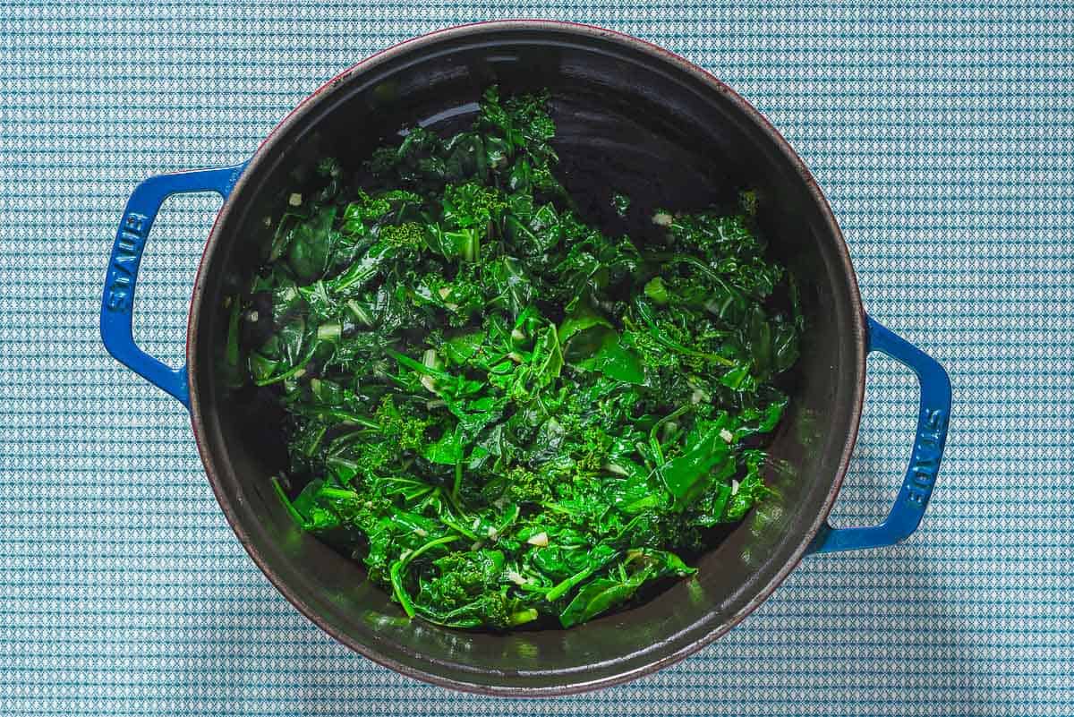 An overhead photo of cooked greens in a large pot.