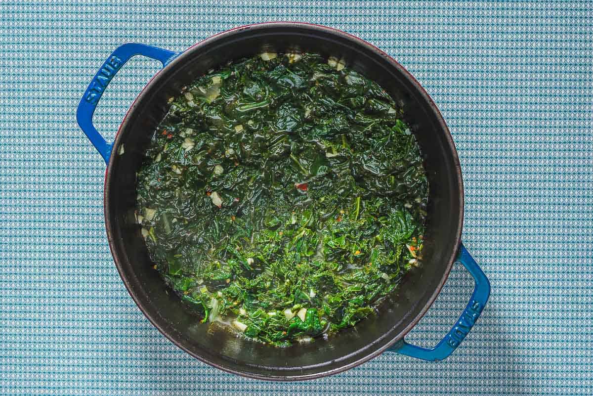 An overhead photo of cooked greens in a large pot.