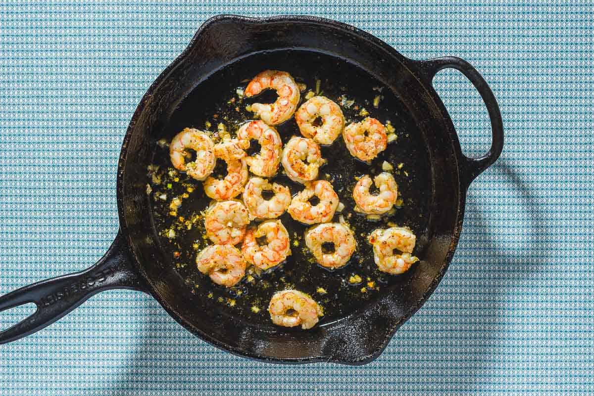 An overhead photo of seared shrimp in a cast iron skillet.