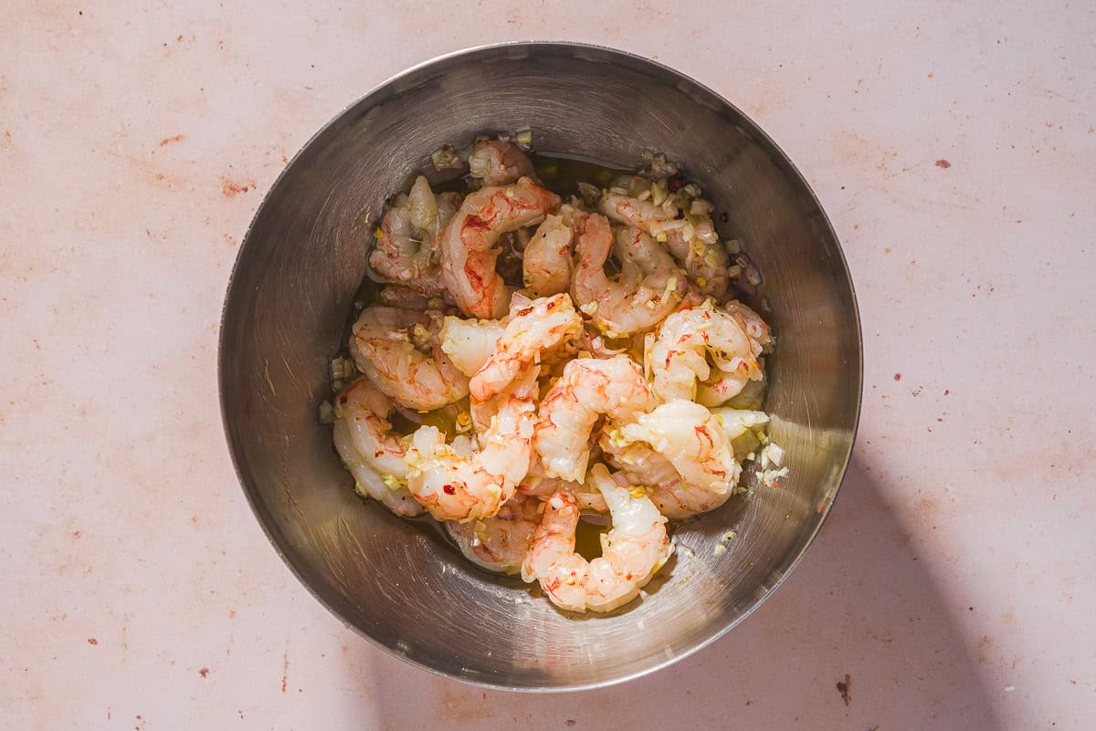 An overhead photo of raw shrimp marinating in a bowl.