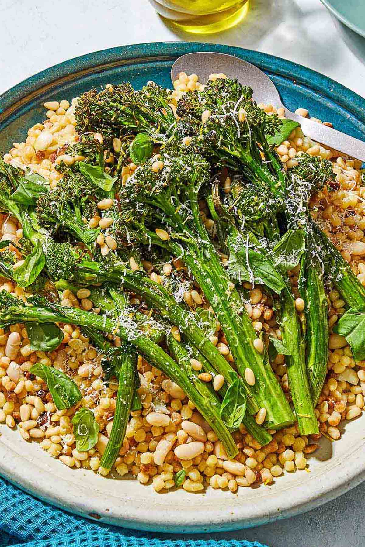 A close of up fregola sarda with broccolini on a platter with a spoon.