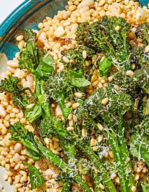 A close up of fregola sarda with broccolini on a platter.