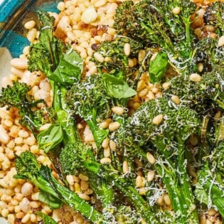 A close up of fregola sarda with broccolini on a platter.