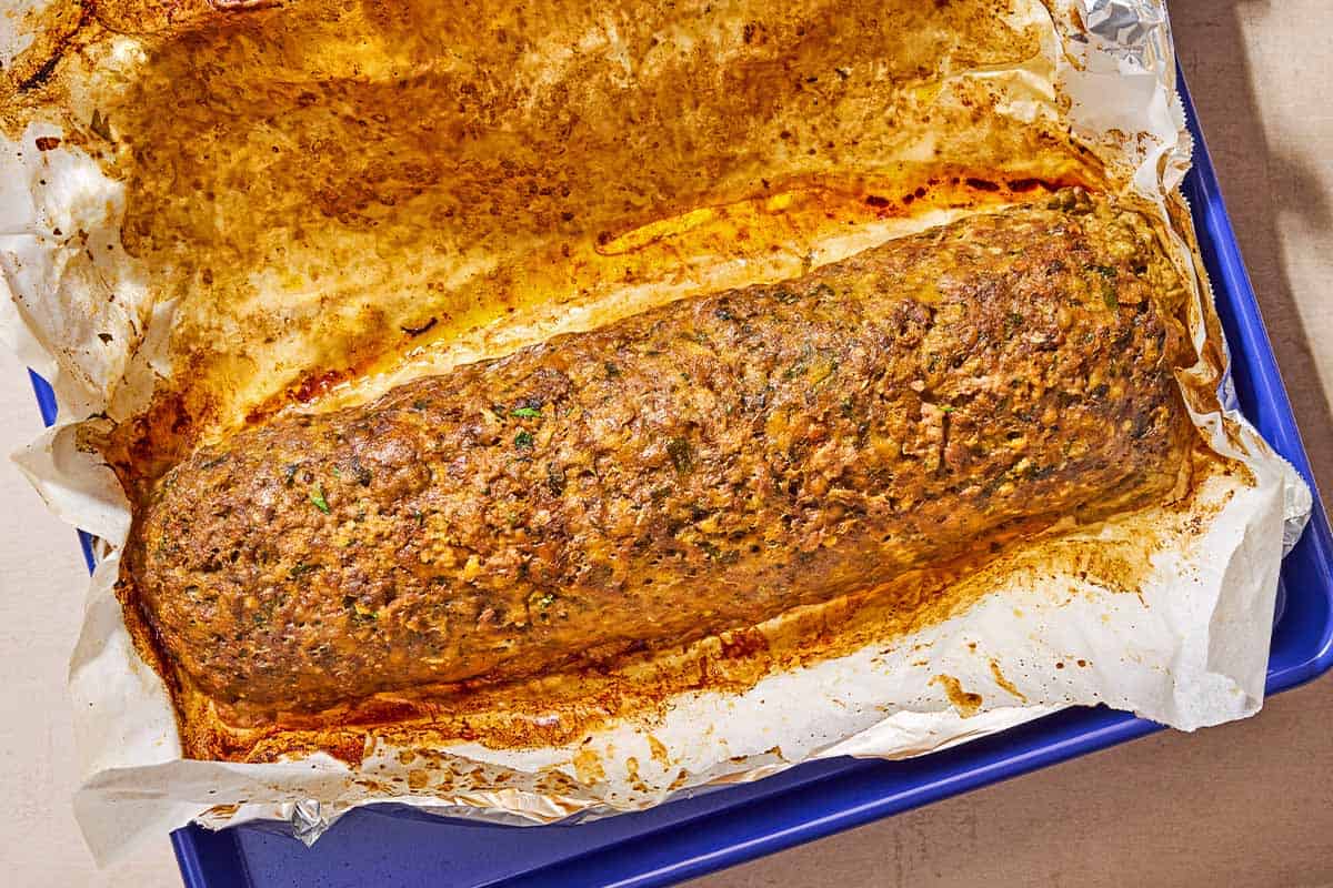 The baked greek meatloaf with hardboiled eggs on a parchment lined sheet pan.