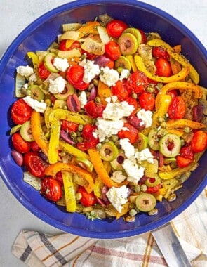 An overhead photo of Mediterranean vegetable medley in a skillet. Next to this is a kitchen towel.