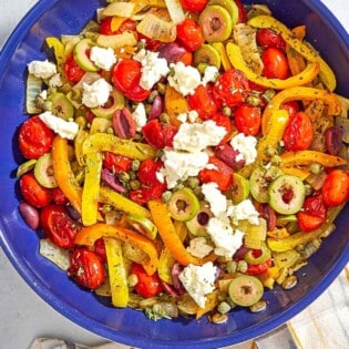 An overhead photo of Mediterranean vegetable medley in a skillet. Next to this is a kitchen towel.