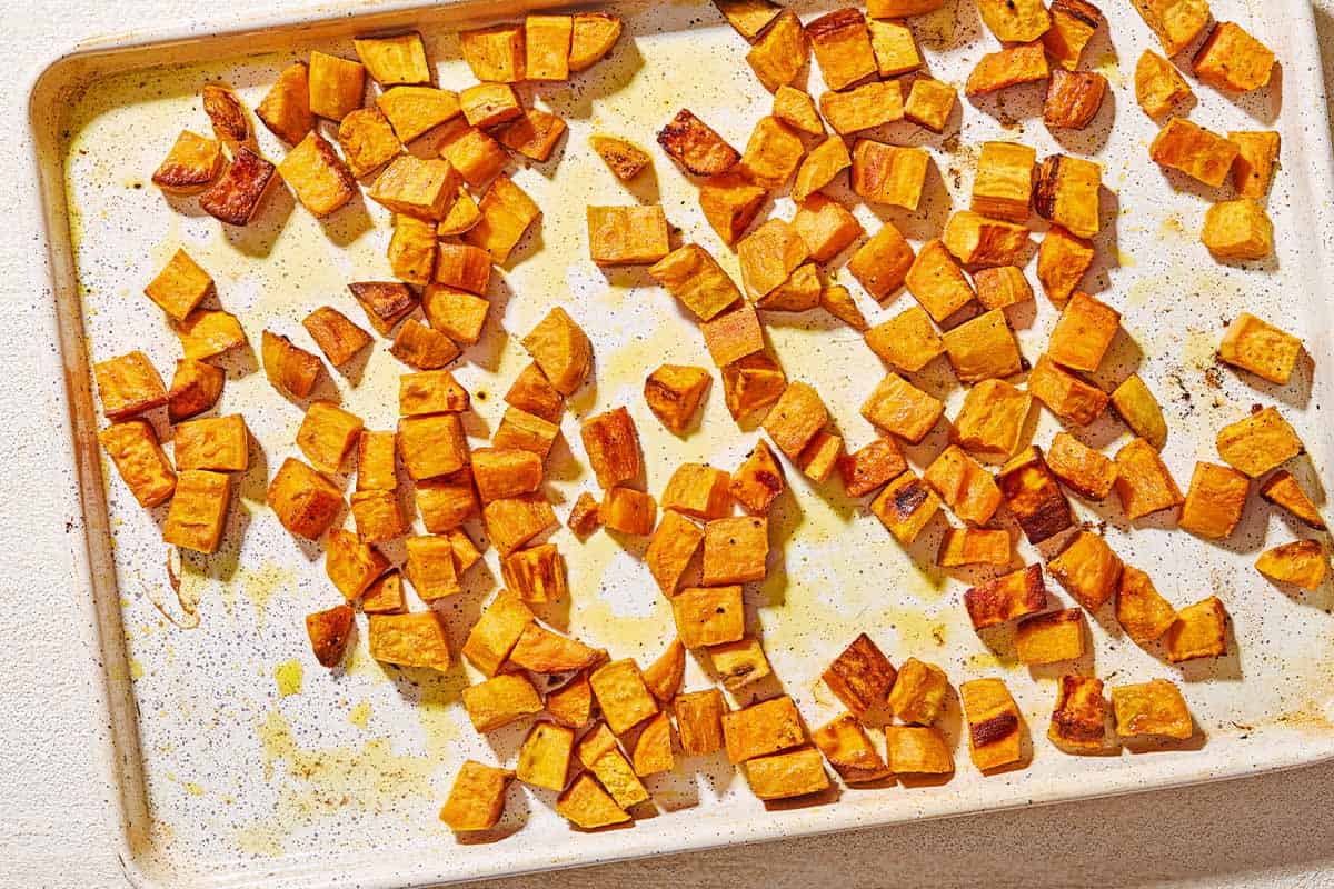 Baked sweet potato cubes on a sheet pan.