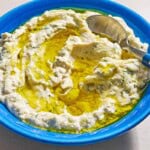 Vegan tzatziki sauce drizzled with olive oil in a bowl with a spoon.