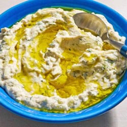 Vegan tzatziki sauce drizzled with olive oil in a bowl with a spoon.