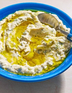 Vegan tzatziki sauce drizzled with olive oil in a bowl with a spoon.