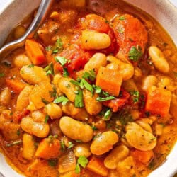 A bowl of white bean stew with a spoon.