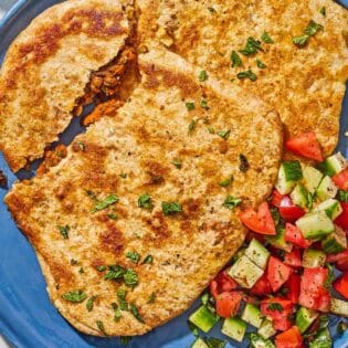 Stuffed flatbreads filled with harissa carrots and lentils on a plate with a cucumber tomato salad.