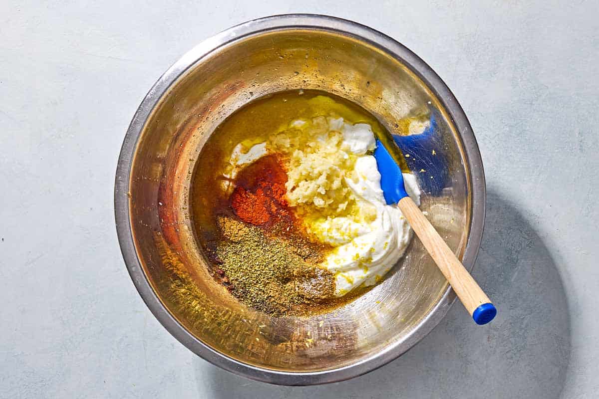 The ingredients for the yogurt marinade in a large bowl just before being mixed together with a spatula.