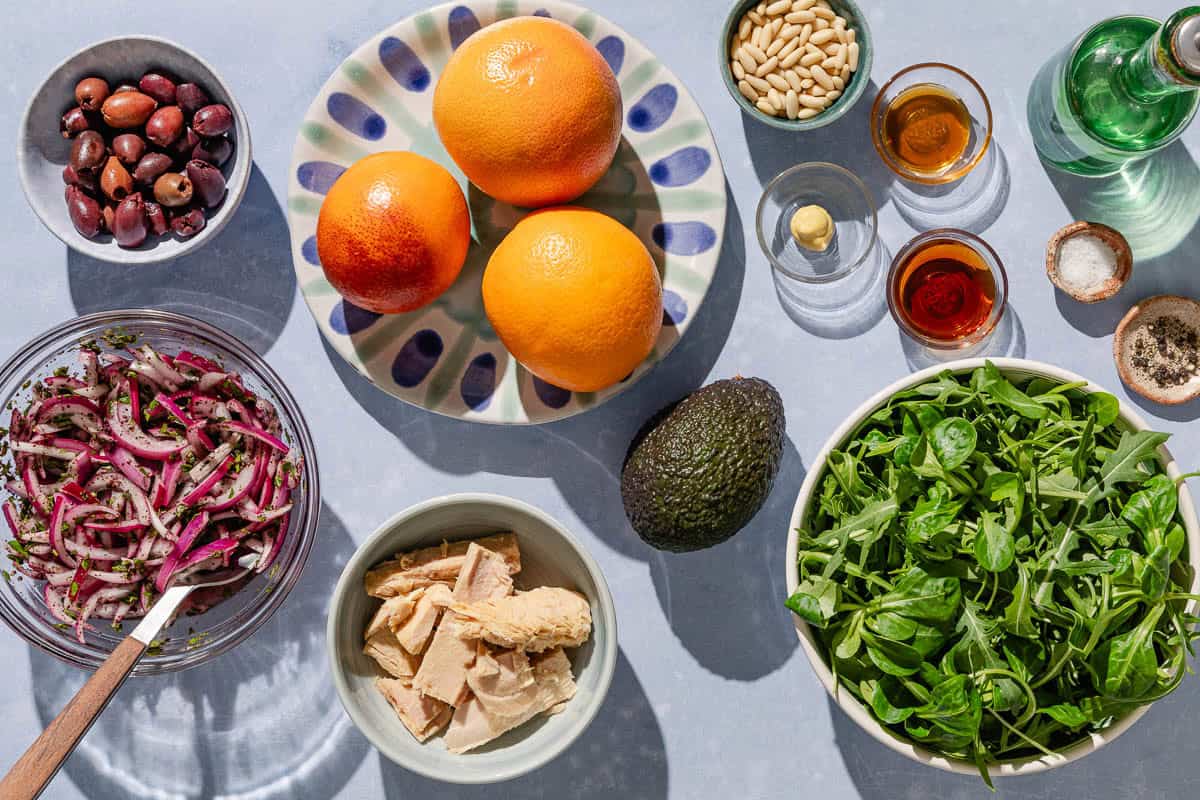 Ingredients for Avocado Tuna Salad including tuna, grapefruit, oranges, baby lettuce, avocado, kalamata olives, pickled red onions, pine nuts, olive oil, sherry vinegar, honey, dijon mustard, salt and black pepper.