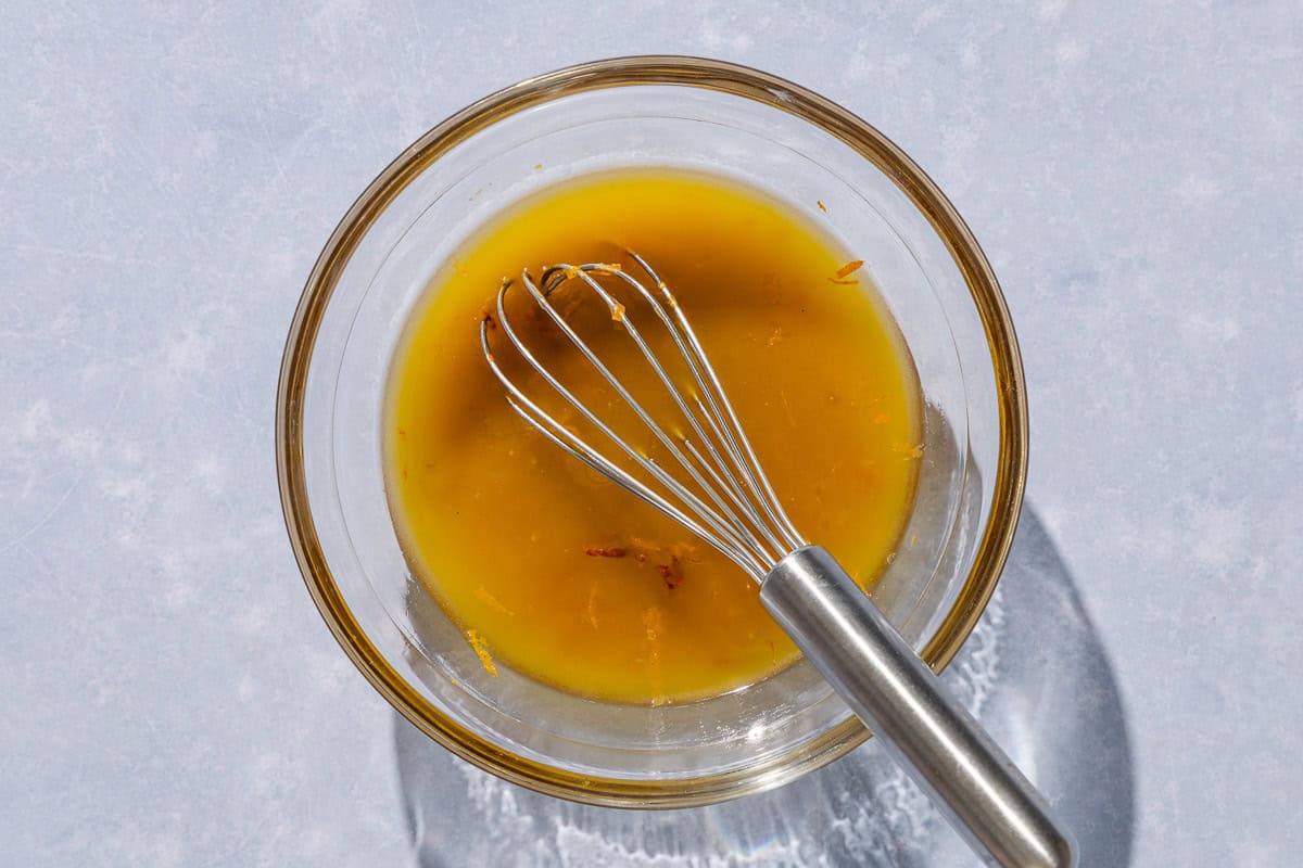 The salad dressing for the avocado tuna salad in a bowl with a whisk.