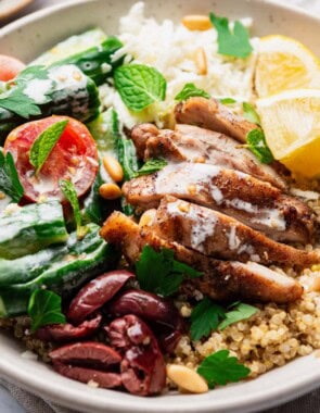 A chicken quinoa bowl topped with chopped parsley and mint.