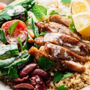 A chicken quinoa bowl topped with chopped parsley and mint.