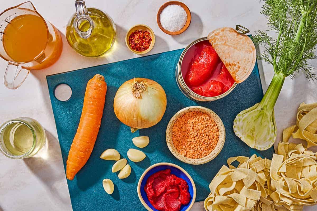 Ingredients for lentil bolognese including red lentils, olive oil, onion, carrot, fennel, tomato paste, garlic, crushed red pepper flakes, white wine, vegetable broth, canned whole tomatoes, salt and pasta.