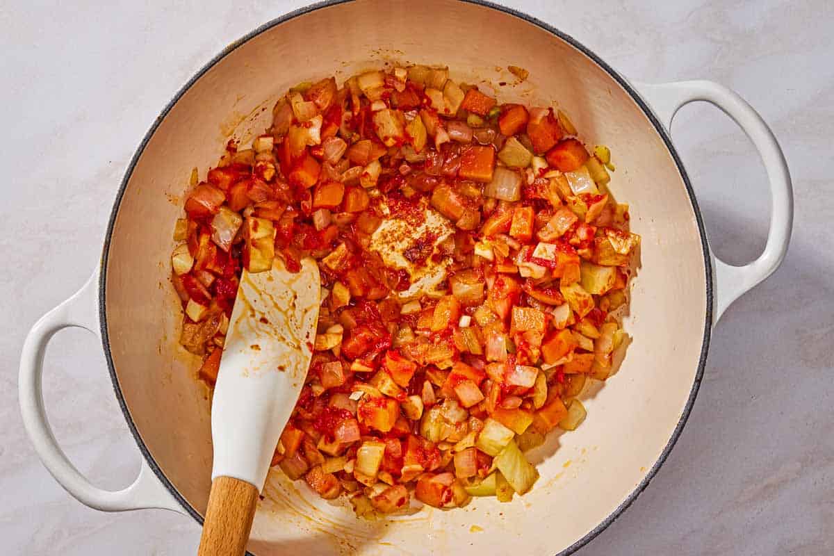 Sauteed chopped onion, carrot, and fennel along with tomato paste, garlic, and red pepper flakes in a pot.