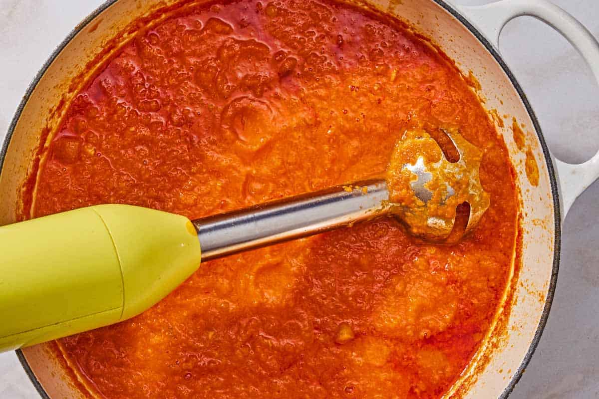 The lentil bolognese in a pot with an immersion blender.