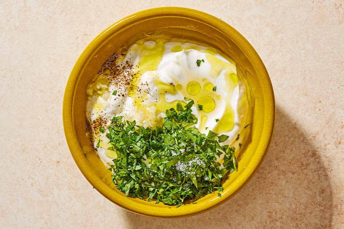 The ingredients for the yogurt herb sauce in a bowl just before being mixed together.