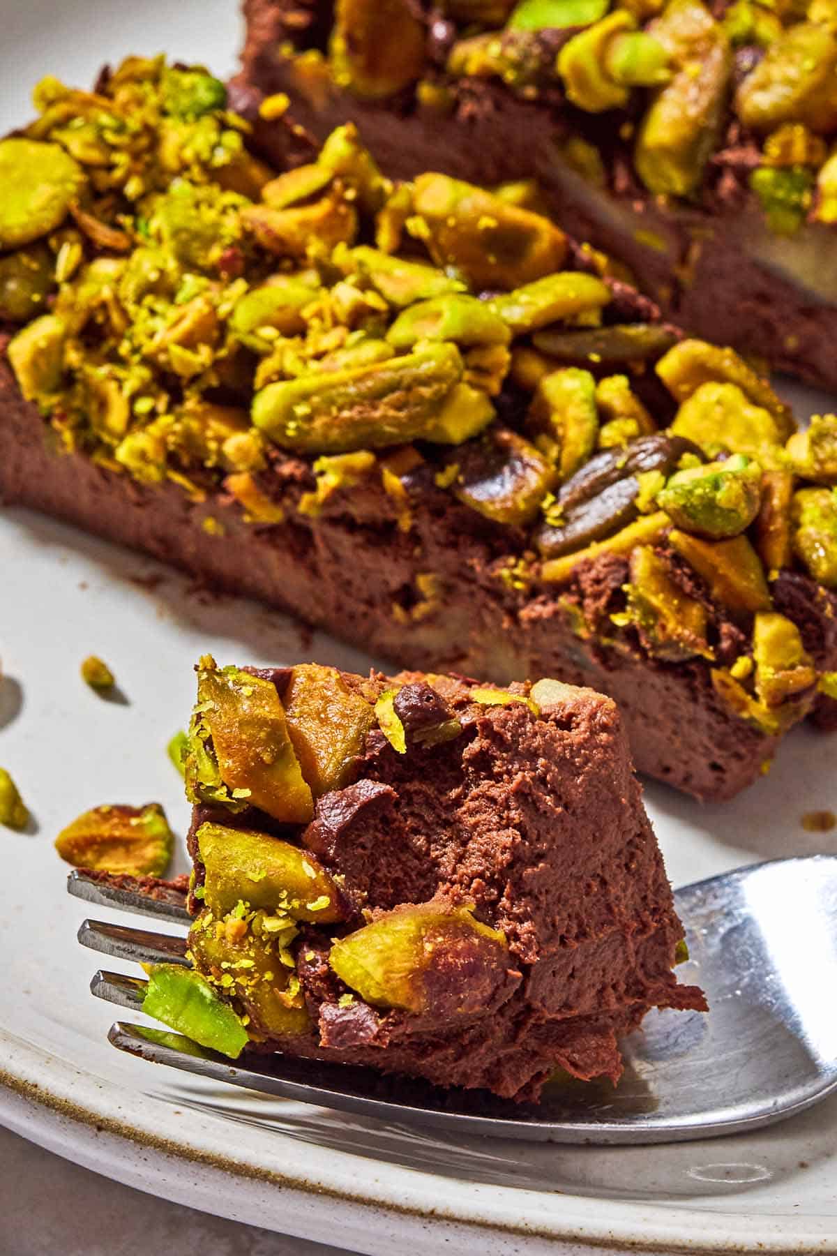 A close up of a piece of vegan chocolate mousse on a fork, with more pieces in the background.