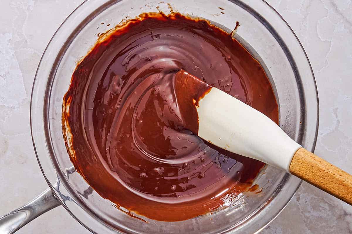 Melted chocolate in a bowl resting on a saucepan.