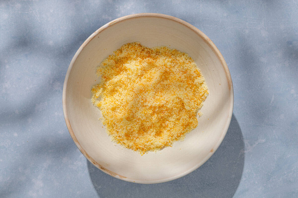 The sugar and orange zest for the orange cake mixed together in a bowl.