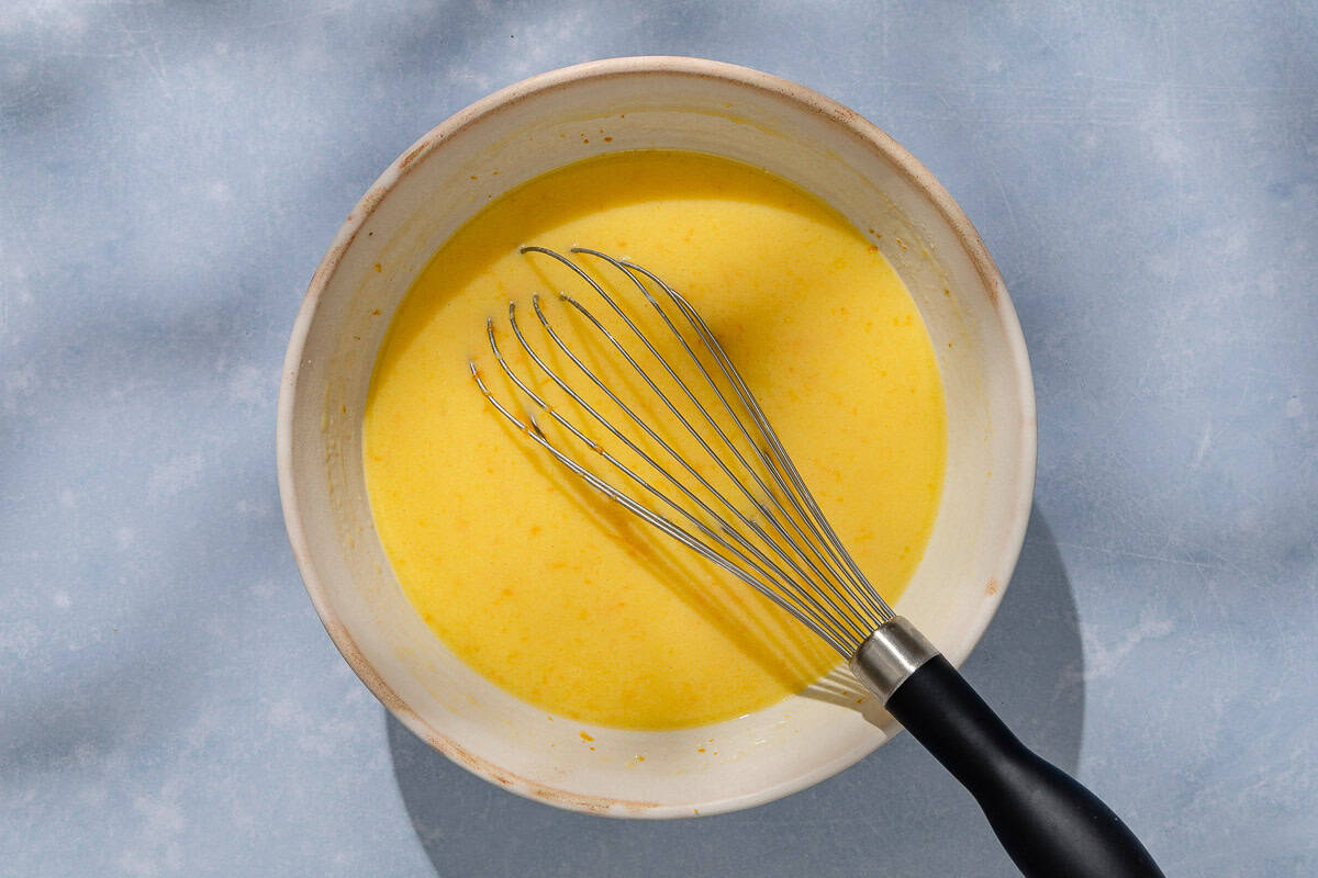 The batter for the orange cake in a bowl with a whisk.