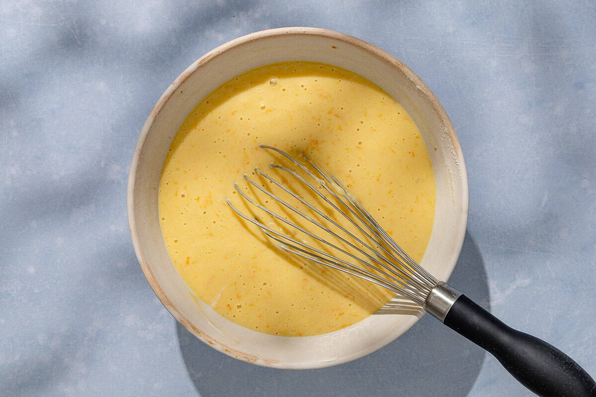 The batter for the orange cake in a bowl with a whisk.